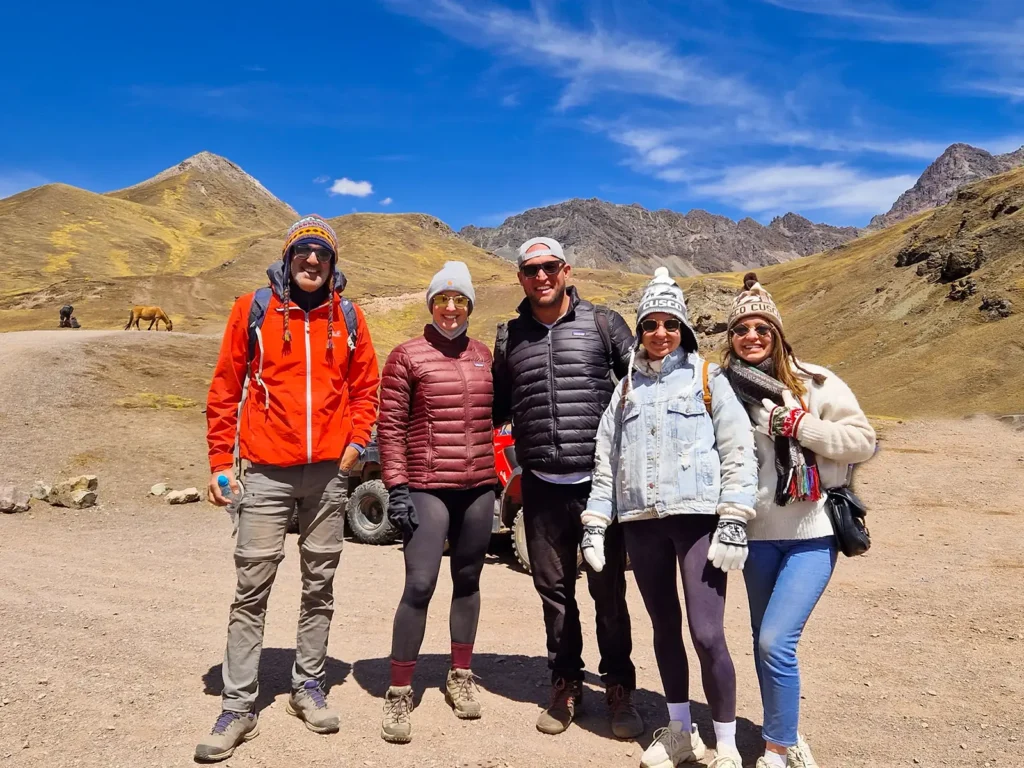 Five travelers posing in an Andean landscape during a Rainbow Mountain tour in Cusco.