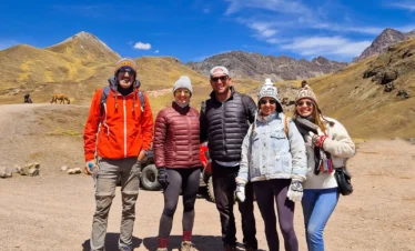 Five travelers posing in an Andean landscape during a Rainbow Mountain tour in Cusco.