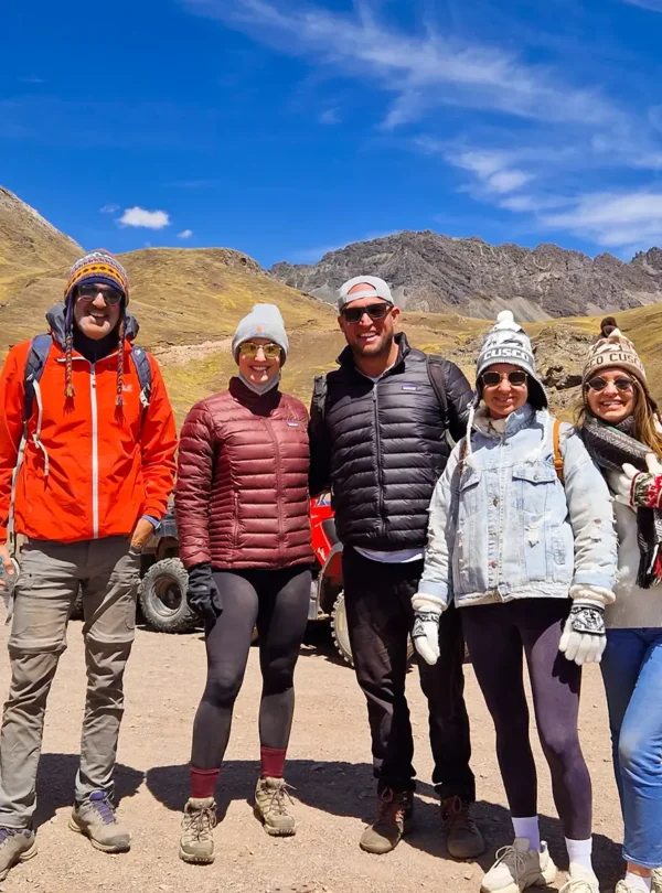 Five travelers posing in an Andean landscape during a Rainbow Mountain tour in Cusco.